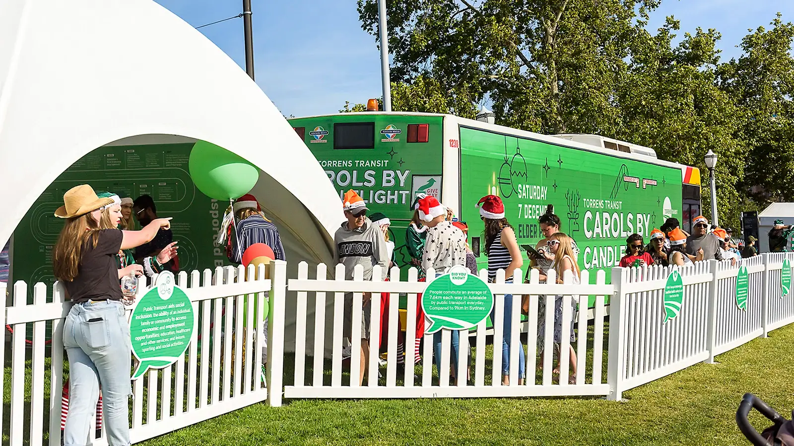 Event signage for Torrens Transit Carols by Candelight Event, including tent with infographic map, bus with full wrap signage, and gate with speech bubble cut out signs.